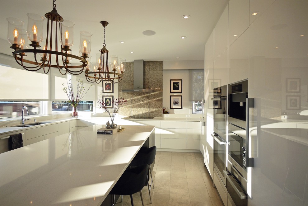 This is an example of a large contemporary u-shaped separate kitchen in Calgary with an undermount sink, flat-panel cabinets, white cabinets, quartz benchtops, multi-coloured splashback, glass tile splashback, stainless steel appliances, travertine floors and with island.