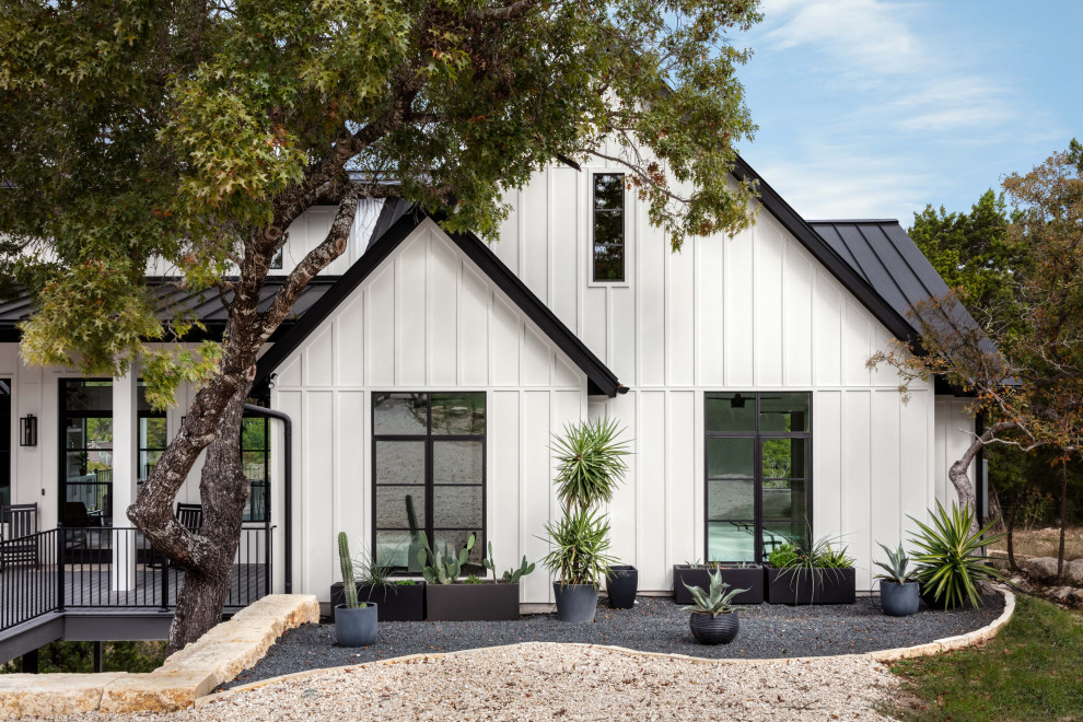 Exemple d'une façade de maison blanche nature en panneau de béton fibré et planches et couvre-joints de taille moyenne et de plain-pied avec un toit à deux pans, un toit en métal et un toit noir.