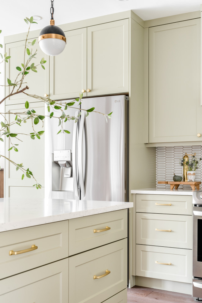 Inspiration for a small transitional brown floor kitchen remodel with shaker cabinets, green cabinets, white backsplash, stainless steel appliances, an island and white countertops