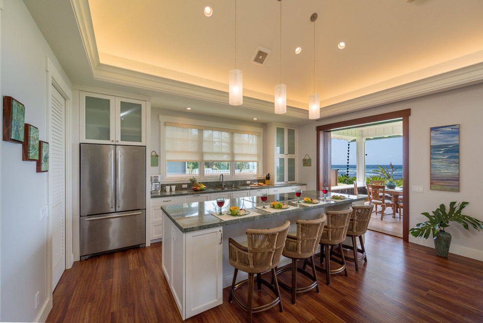 Inspiration for a beach style single-wall kitchen in Hawaii with an undermount sink, shaker cabinets, white cabinets, granite benchtops, green splashback, stainless steel appliances, vinyl floors, with island, brown floor and green benchtop.