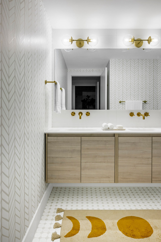 Imagen de cuarto de baño principal y doble costero con armarios con paneles lisos, puertas de armario de madera clara, baldosas y/o azulejos blancos, encimeras blancas y papel pintado