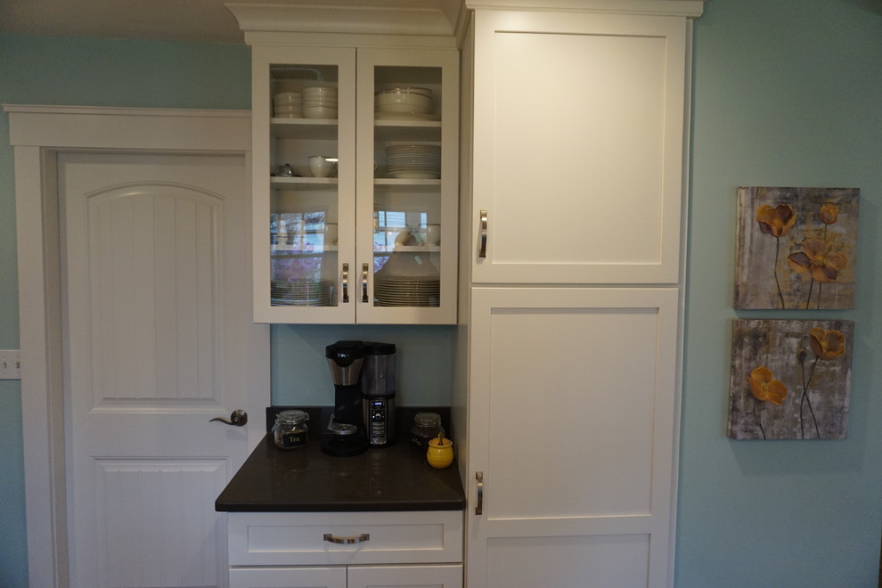 Eat-in kitchen - mid-sized transitional u-shaped medium tone wood floor eat-in kitchen idea in Boston with an undermount sink, shaker cabinets, gray cabinets, quartz countertops, black backsplash, stainless steel appliances and an island