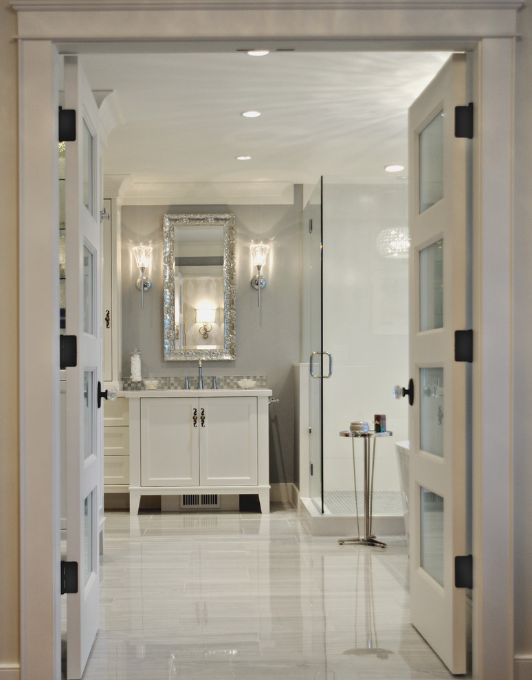 Large traditional master bathroom in Vancouver with recessed-panel cabinets, white cabinets, a freestanding tub, a corner shower, a two-piece toilet, gray tile, stone tile, grey walls, marble floors, an undermount sink and engineered quartz benchtops.