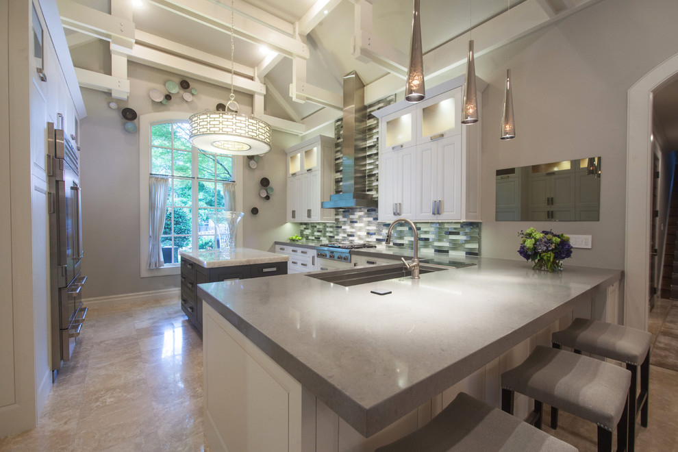 Kitchen - large transitional u-shaped porcelain tile and beige floor kitchen idea with raised-panel cabinets, white cabinets, gray backsplash, glass tile backsplash, stainless steel appliances, an island, an undermount sink and solid surface countertops