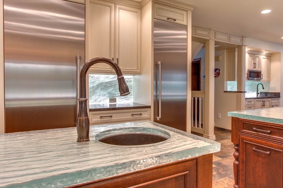 Photo of an expansive traditional u-shaped eat-in kitchen in Denver with an undermount sink, recessed-panel cabinets, distressed cabinets, glass benchtops, blue splashback, glass sheet splashback, stainless steel appliances, slate floors, multiple islands and turquoise benchtop.