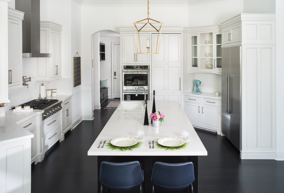 Mid-sized transitional u-shaped dark wood floor, black floor and tray ceiling kitchen photo in Orlando with a farmhouse sink, shaker cabinets, white cabinets, quartz countertops, white backsplash, quartz backsplash, stainless steel appliances, an island and white countertops