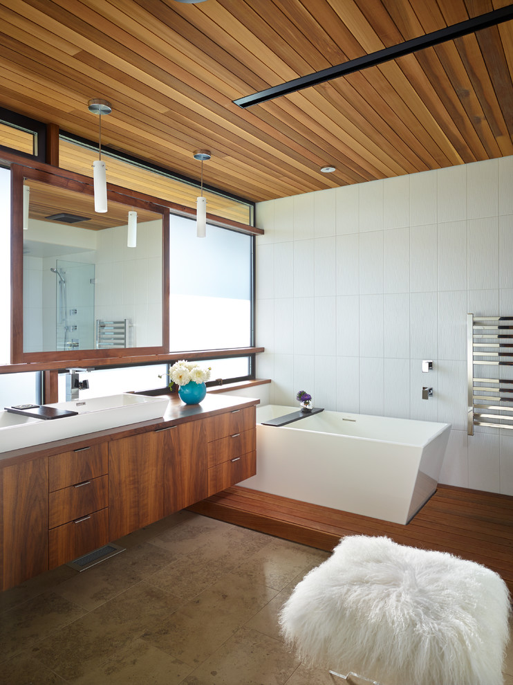 Photo of a contemporary bathroom in Seattle with a vessel sink, flat-panel cabinets, medium wood cabinets, a freestanding tub and white tile.