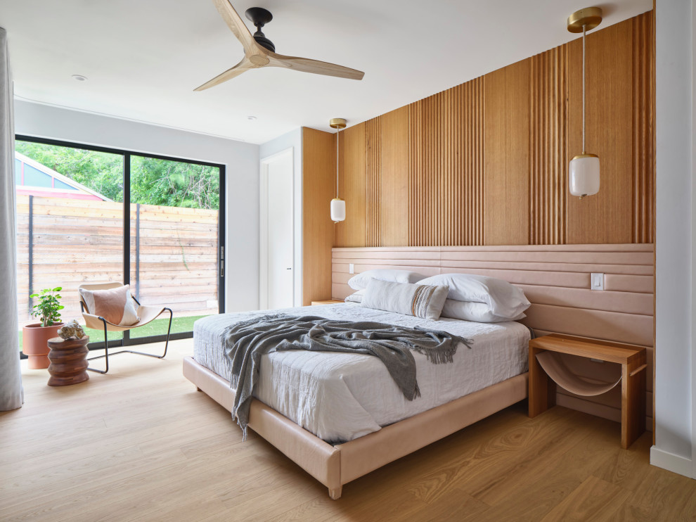 This is an example of a contemporary bedroom in Austin with grey walls, medium hardwood floors, brown floor and wood walls.