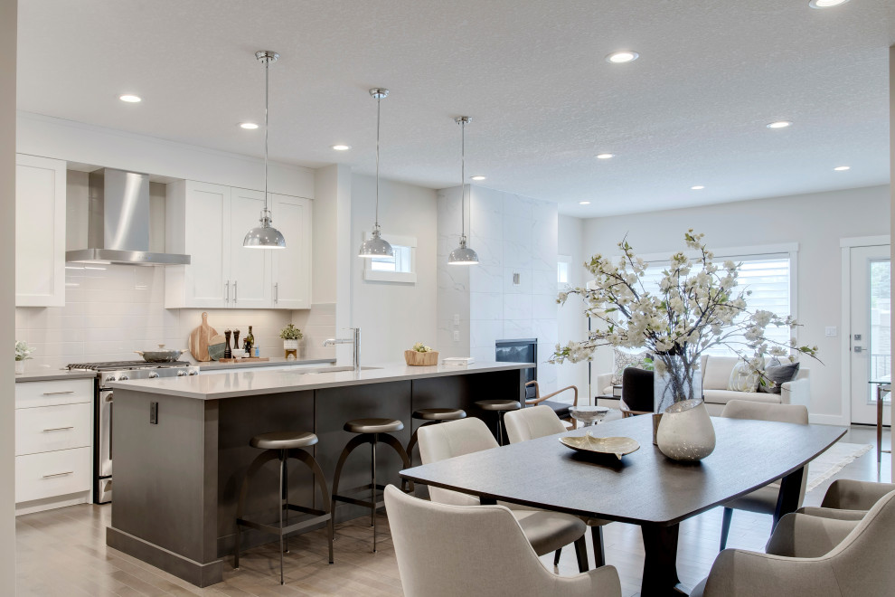 Inspiration for a large contemporary kitchen in Calgary with shaker cabinets, white cabinets, quartzite benchtops, white splashback, stainless steel appliances, medium hardwood floors, with island, grey floor and grey benchtop.