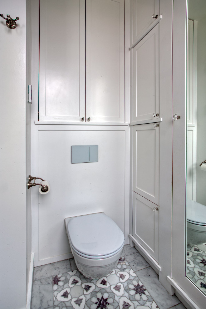 Cette photo montre une douche en alcôve principale chic de taille moyenne avec un placard à porte shaker, des portes de placard blanches, WC suspendus, un carrelage blanc, un carrelage de pierre, un mur blanc, un sol en marbre, un lavabo encastré, un plan de toilette en marbre, un sol violet, une cabine de douche à porte battante, un plan de toilette blanc, meuble double vasque, meuble-lavabo encastré, un plafond à caissons et du lambris.