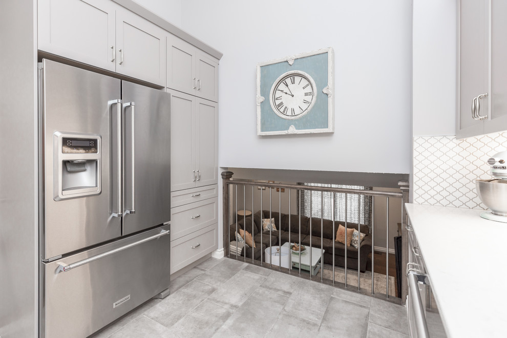 Eat-in kitchen - transitional gray floor eat-in kitchen idea in Calgary with a farmhouse sink, shaker cabinets, gray cabinets, quartz countertops, white backsplash, stainless steel appliances and glass sheet backsplash