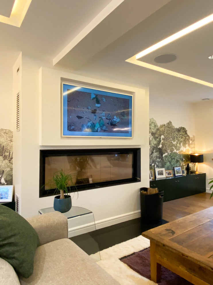 Réalisation d'un grand salon beige et blanc bohème ouvert avec un mur blanc, parquet clair, une cheminée standard, un téléviseur encastré, un sol marron, un plafond décaissé, du papier peint et un escalier.