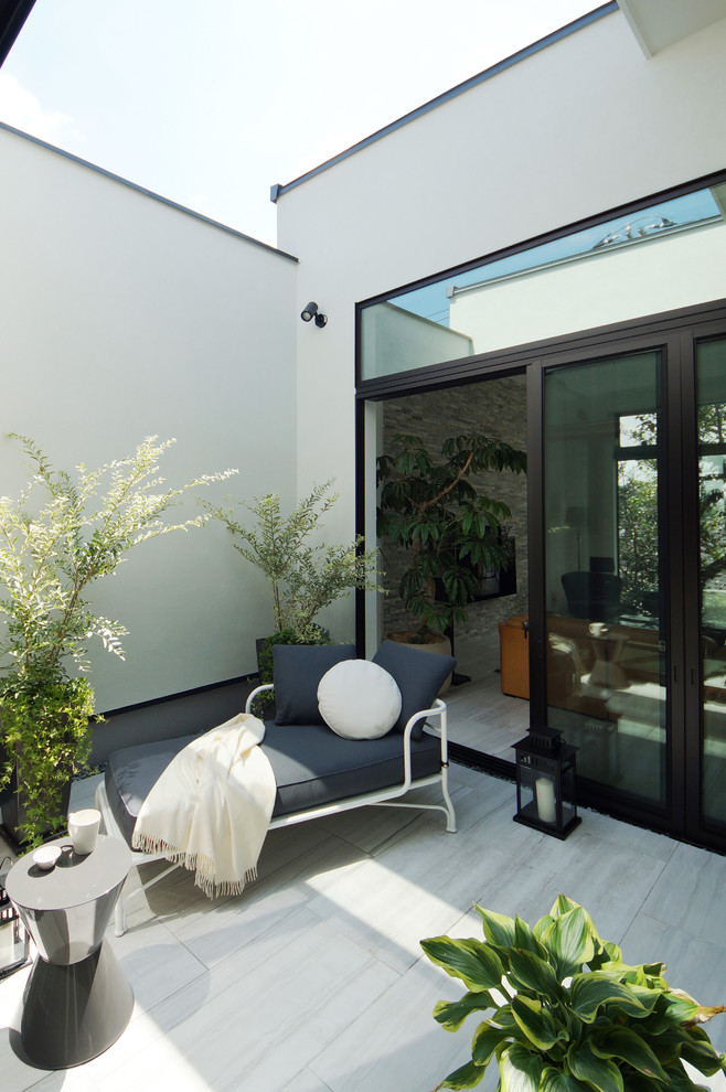 This is an example of a mid-sized contemporary courtyard patio in Tokyo with a container garden and natural stone pavers.