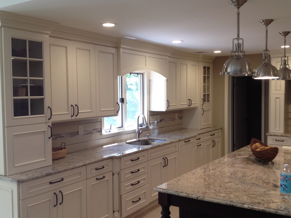 Photo of a large transitional l-shaped separate kitchen in New York with an undermount sink, raised-panel cabinets, white cabinets, granite benchtops, grey splashback, stone tile splashback, stainless steel appliances, dark hardwood floors, with island and brown floor.