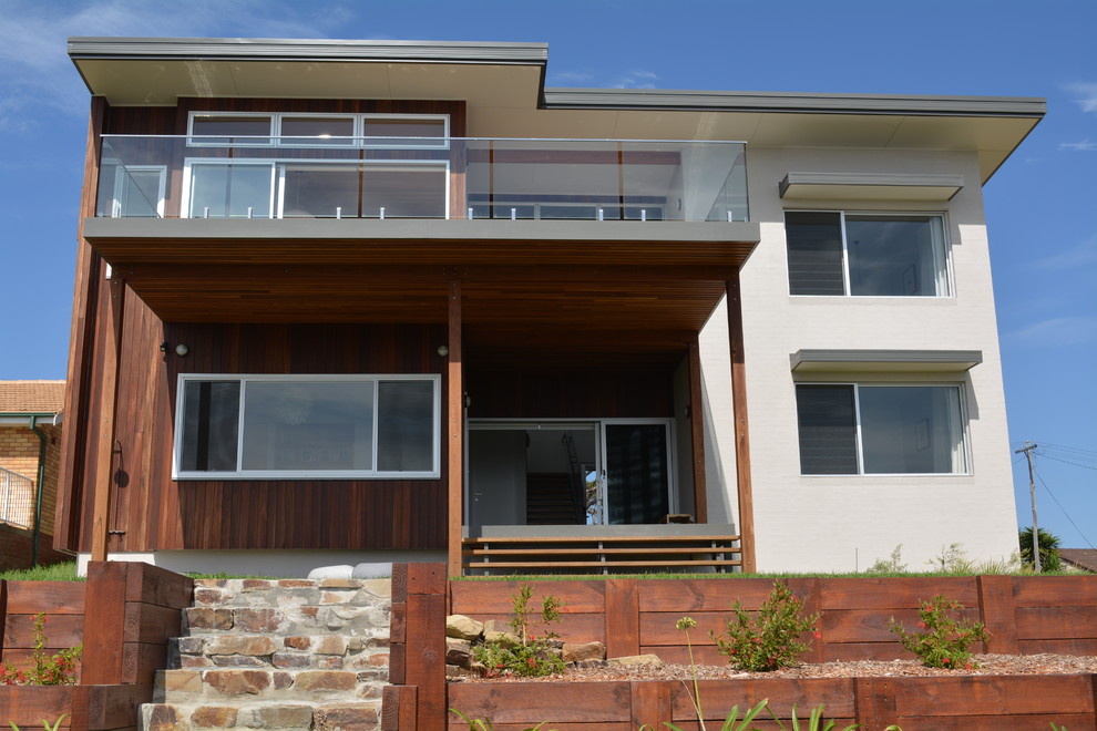 Photo of a large contemporary two-storey beige exterior in Other with wood siding and a flat roof.