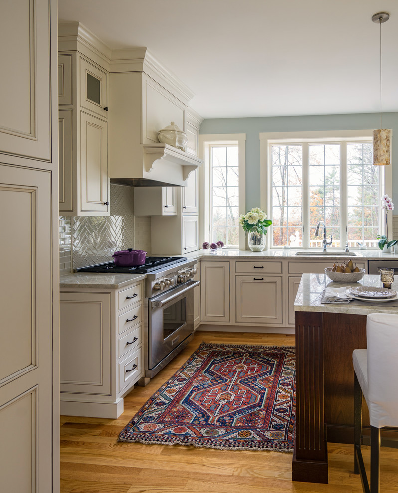 Design ideas for a large traditional l-shaped eat-in kitchen in Boston with an undermount sink, recessed-panel cabinets, white cabinets, granite benchtops, grey splashback, glass tile splashback, stainless steel appliances, light hardwood floors, with island and brown floor.