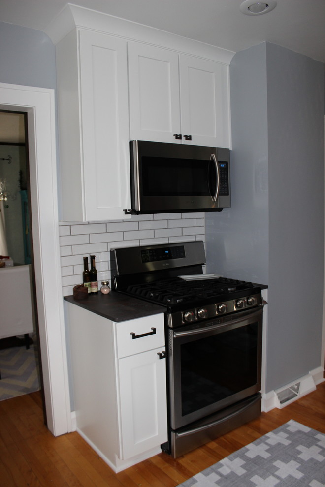 Exempel på ett avskilt, mellanstort klassiskt flerfärgad flerfärgat u-kök, med en rustik diskho, luckor med glaspanel, vita skåp, vitt stänkskydd, stänkskydd i tunnelbanekakel, rostfria vitvaror, mellanmörkt trägolv och brunt golv