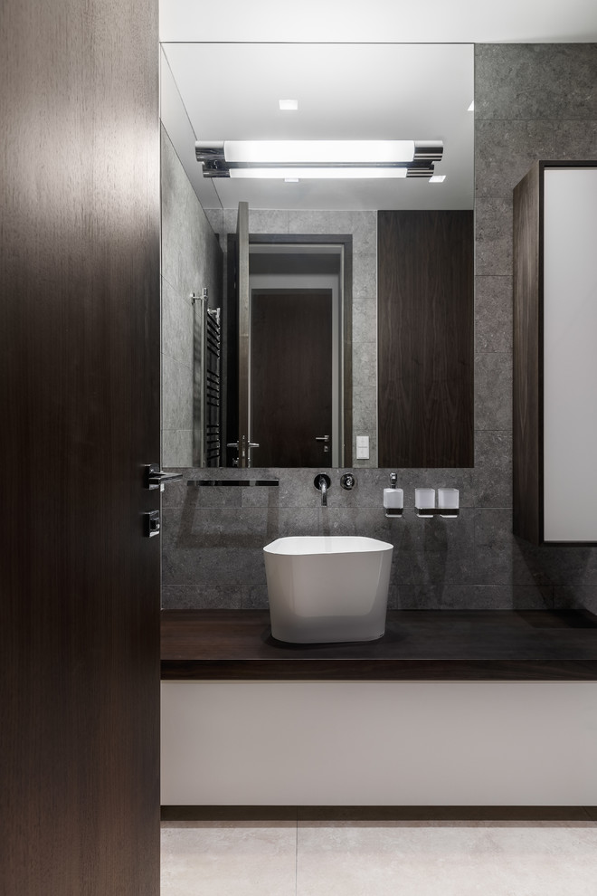 Photo of a small contemporary bathroom in Moscow with flat-panel cabinets, white cabinets, gray tile, porcelain tile, porcelain floors, a vessel sink and wood benchtops.