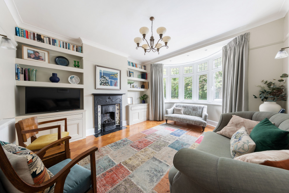 Immagine di un soggiorno classico con pareti beige, pavimento in legno massello medio, camino classico, TV autoportante e pavimento marrone