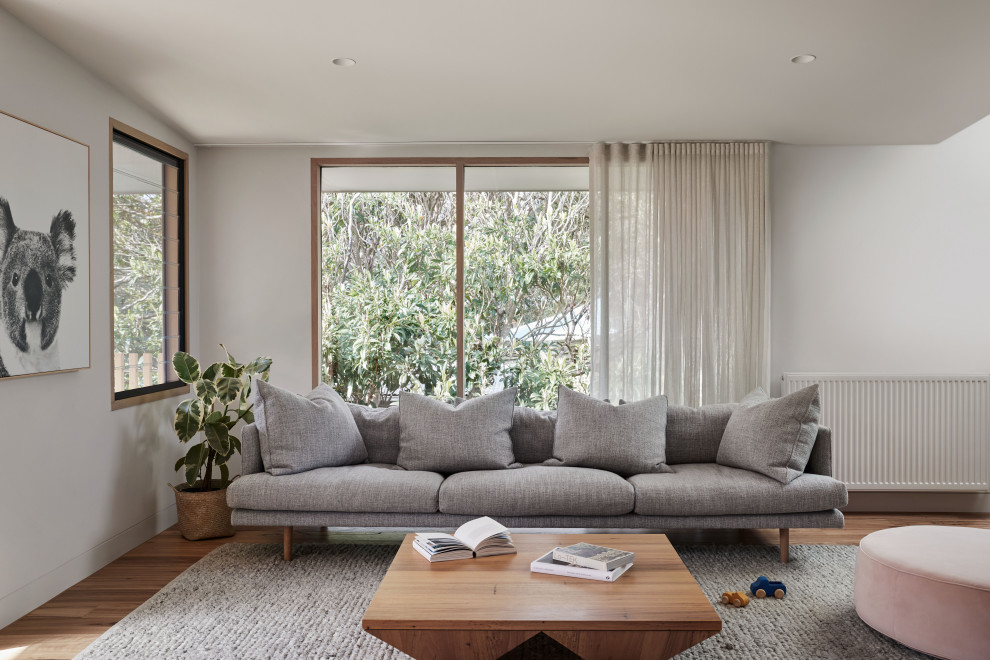 This is an example of a medium sized beach style open plan living room in Melbourne with a music area, white walls and medium hardwood flooring.