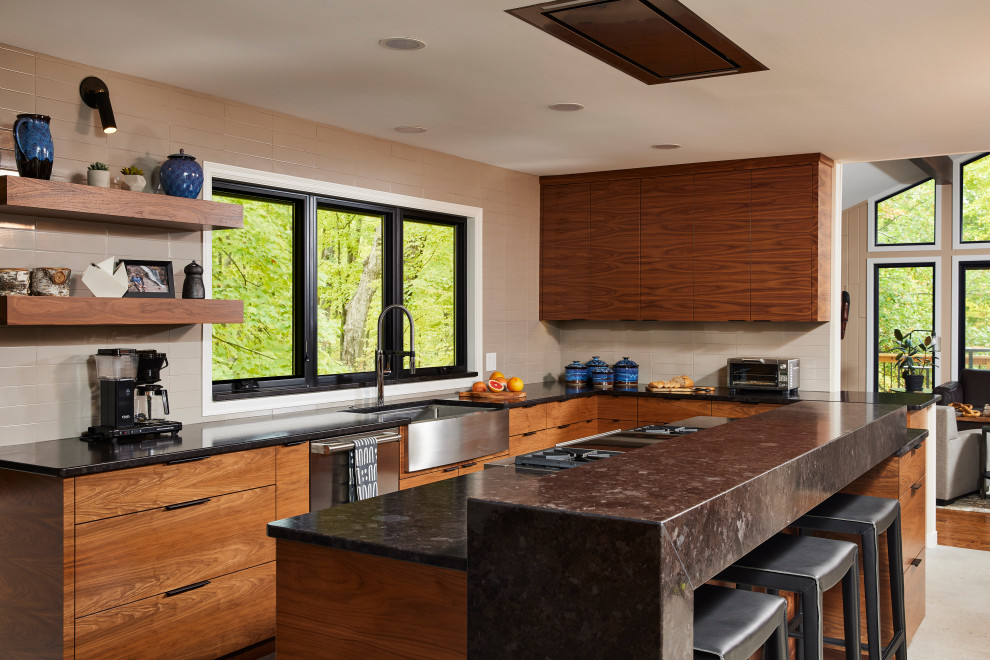 Inspiration for a large transitional u-shaped porcelain tile and gray floor enclosed kitchen remodel in Minneapolis with a farmhouse sink, flat-panel cabinets, medium tone wood cabinets, granite countertops, gray backsplash, ceramic backsplash, stainless steel appliances, an island and black countertops