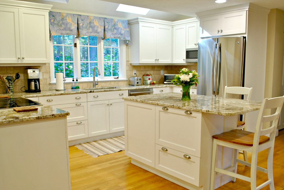 Photo of a mid-sized traditional u-shaped eat-in kitchen in Boston with an undermount sink, recessed-panel cabinets, white cabinets, granite benchtops, beige splashback, stainless steel appliances, medium hardwood floors and with island.