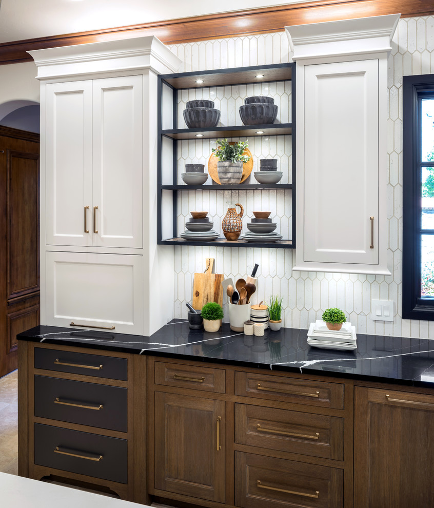 This is an example of a large country l-shaped separate kitchen in Oklahoma City with an undermount sink, white cabinets, quartz benchtops, white splashback, porcelain splashback, panelled appliances, marble floors, with island and black benchtop.