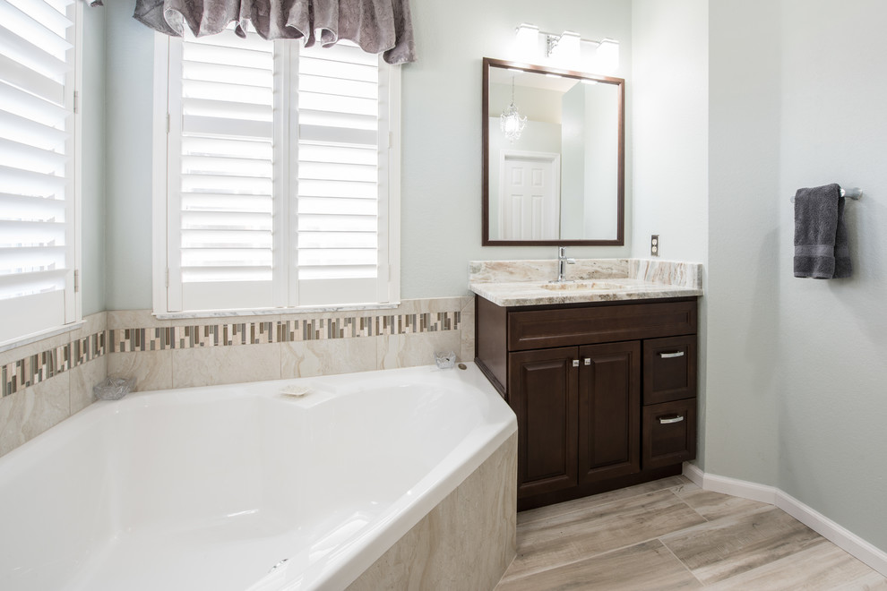 Expansive transitional master bathroom in Orlando with raised-panel cabinets, dark wood cabinets, a corner tub, beige tile, ceramic tile, ceramic floors, an undermount sink, granite benchtops, multi-coloured floor, a hinged shower door and multi-coloured benchtops.