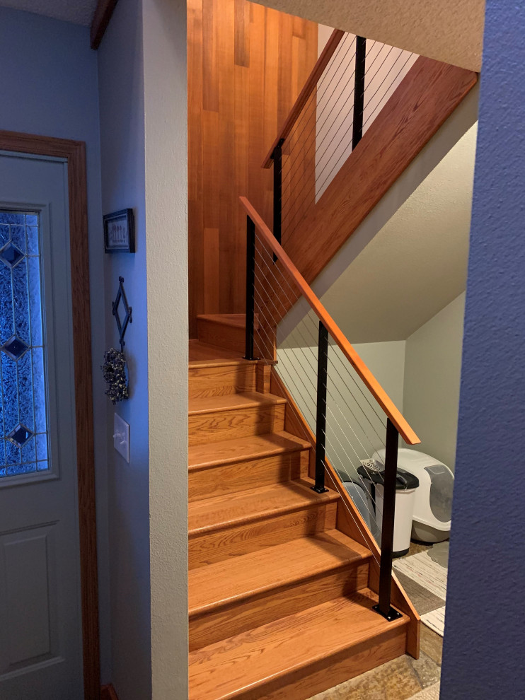 Mid-sized transitional wood l-shaped staircase in Other with wood risers, cable railing and wood walls.