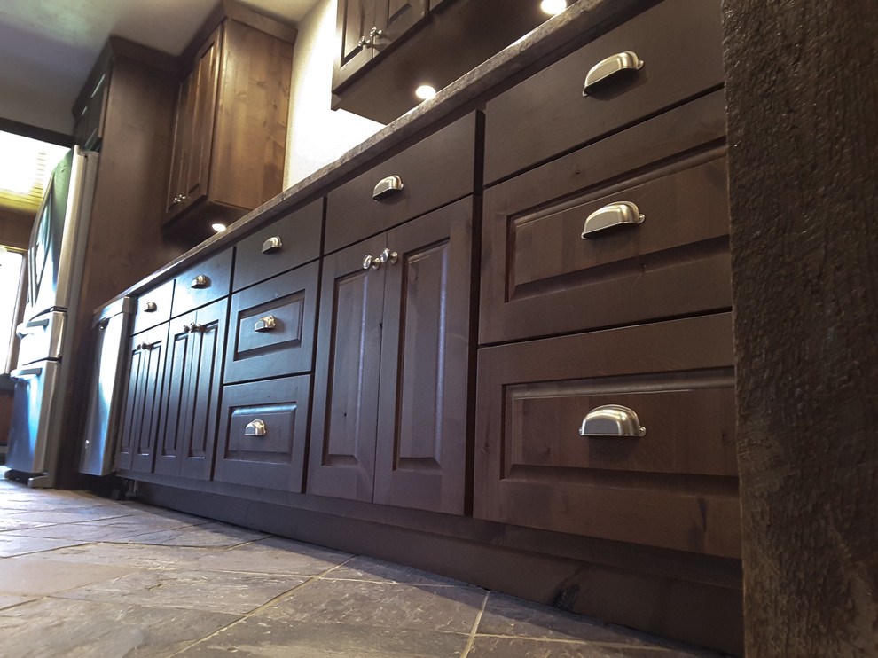 Inspiration for a mid-sized rustic galley slate floor and beige floor kitchen pantry remodel with raised-panel cabinets, dark wood cabinets, granite countertops, an undermount sink, stainless steel appliances and no island