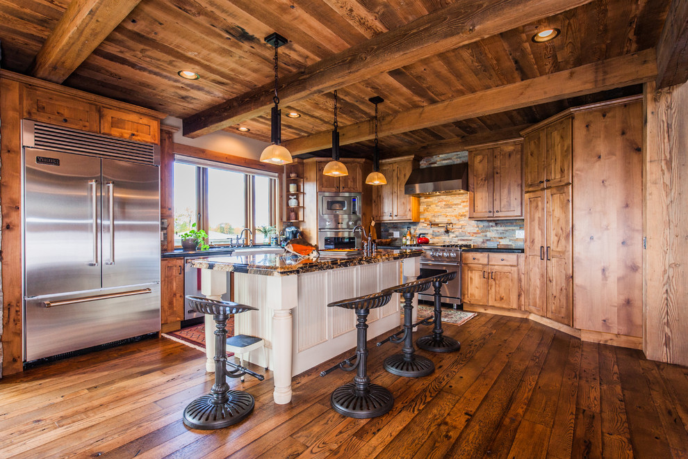 Example of a mid-sized mountain style l-shaped dark wood floor open concept kitchen design with a farmhouse sink, shaker cabinets, medium tone wood cabinets, granite countertops, multicolored backsplash, stone tile backsplash, stainless steel appliances and an island