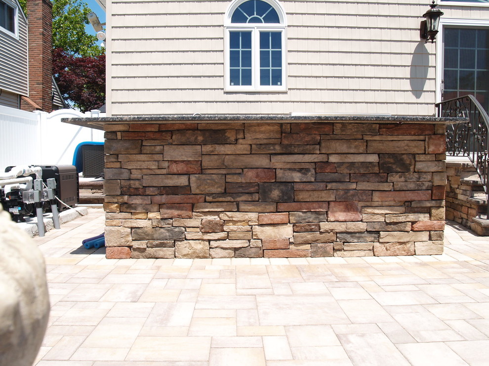 Mid-sized traditional backyard patio in New York with an outdoor kitchen, natural stone pavers and no cover.