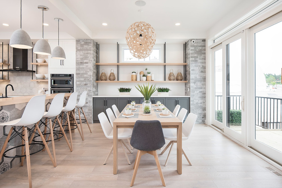Photo of a mid-sized scandinavian open plan dining in Calgary with white walls, light hardwood floors, a standard fireplace and beige floor.