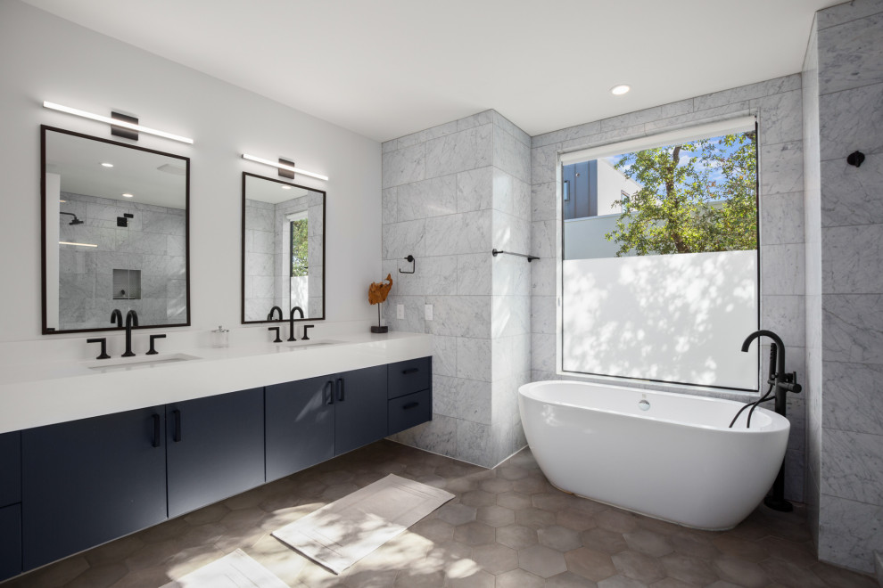 This is an example of a mid-sized contemporary master bathroom in Austin with flat-panel cabinets, a freestanding tub, marble, white walls, porcelain floors, an undermount sink, marble benchtops, grey floor, white benchtops, an enclosed toilet, a double vanity and a floating vanity.
