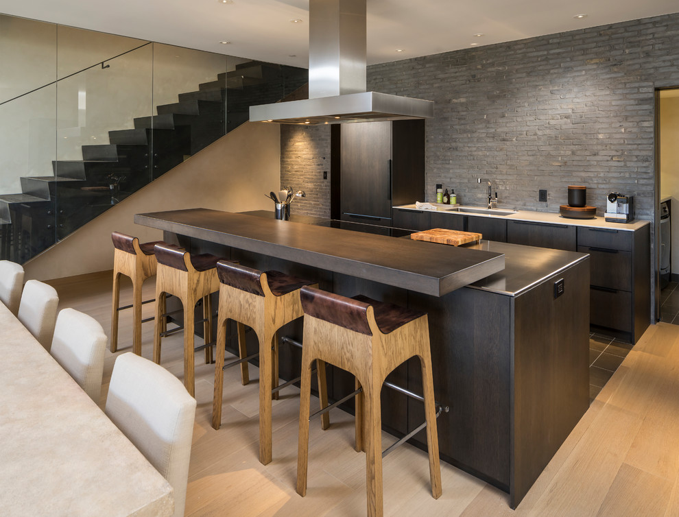This is an example of an expansive contemporary galley eat-in kitchen in Salt Lake City with flat-panel cabinets, dark wood cabinets, with island, an undermount sink, stainless steel benchtops, grey splashback, panelled appliances, light hardwood floors, beige floor and grey benchtop.