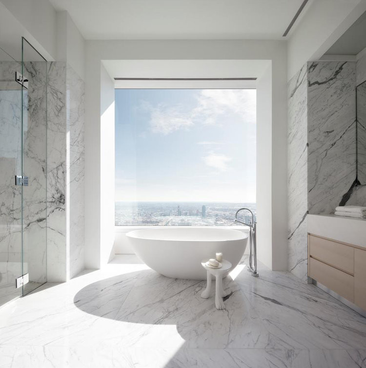 This is an example of a contemporary bathroom in New York with a freestanding tub, black and white tile, marble, marble floors, an integrated sink, a hinged shower door and white benchtops.