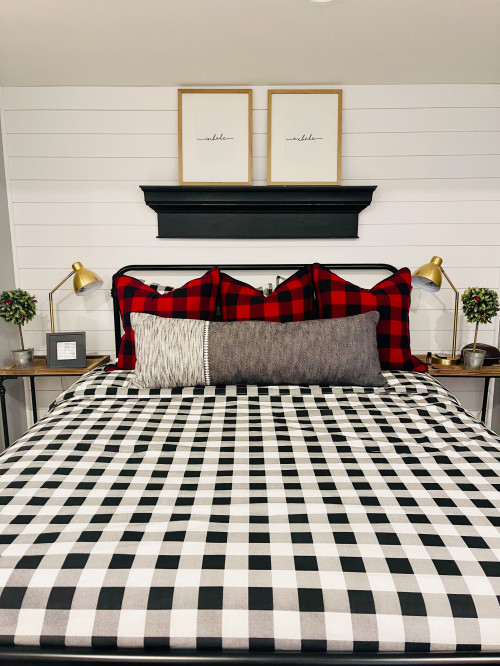 Cozy bedroom with layered red and plaid throw pillows and gray bedding for a Christmas-themed room.