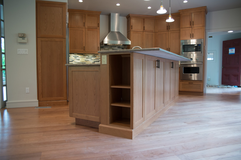 Inspiration for a large transitional l-shaped medium tone wood floor eat-in kitchen remodel with a double-bowl sink, recessed-panel cabinets, medium tone wood cabinets, concrete countertops, multicolored backsplash, matchstick tile backsplash, stainless steel appliances and an island