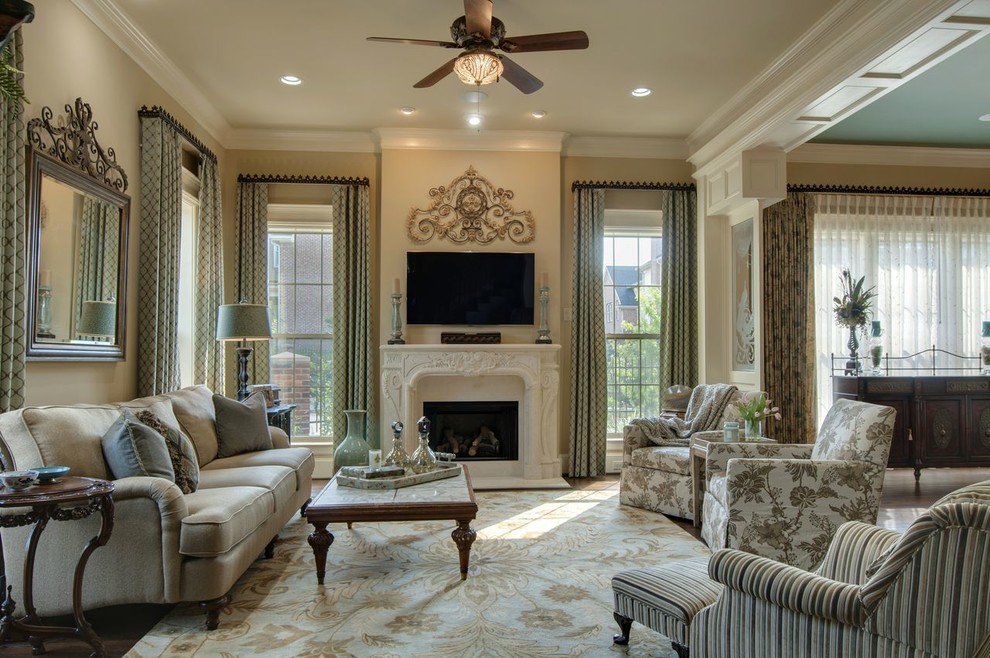 Mid-sized traditional enclosed family room in Houston with beige walls, medium hardwood floors, a standard fireplace, a plaster fireplace surround, a wall-mounted tv and brown floor.