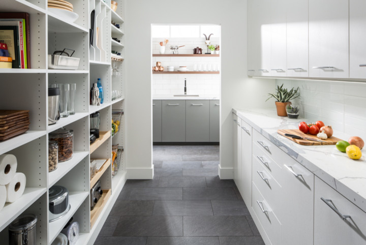 This is an example of a mid-sized transitional u-shaped kitchen pantry in Charleston with flat-panel cabinets, white cabinets, marble benchtops, white splashback, glass tile splashback, slate floors and grey floor.