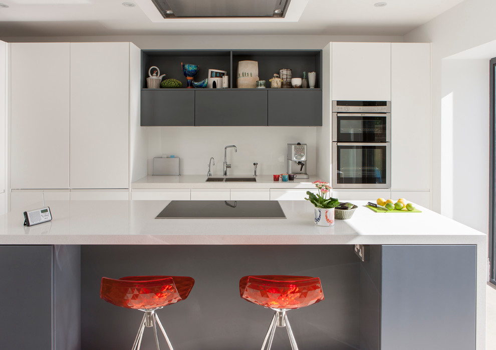 Inspiration for a large contemporary open plan kitchen in London with an integrated sink, flat-panel cabinets, grey cabinets, granite benchtops, glass sheet splashback, black appliances and with island.
