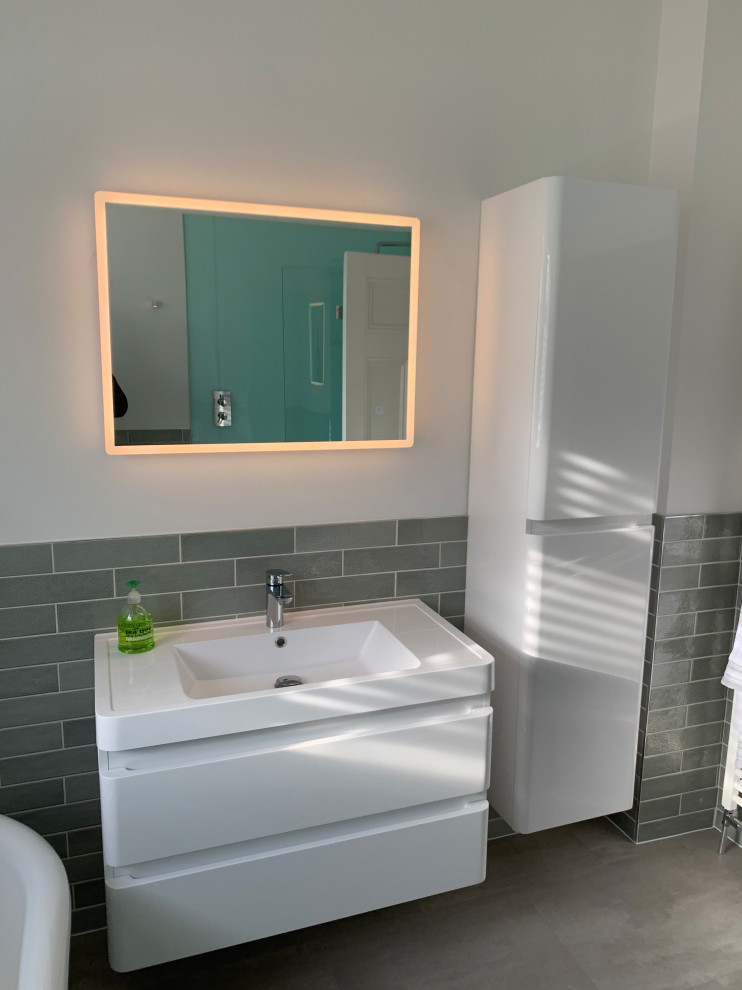 This is an example of a mid-sized contemporary kids bathroom in Sussex with flat-panel cabinets, white cabinets, a freestanding tub, a corner shower, a two-piece toilet, blue tile, pebble tile, white walls, vinyl floors, an integrated sink, grey floor, a sliding shower screen, white benchtops, an enclosed toilet, a single vanity and a floating vanity.
