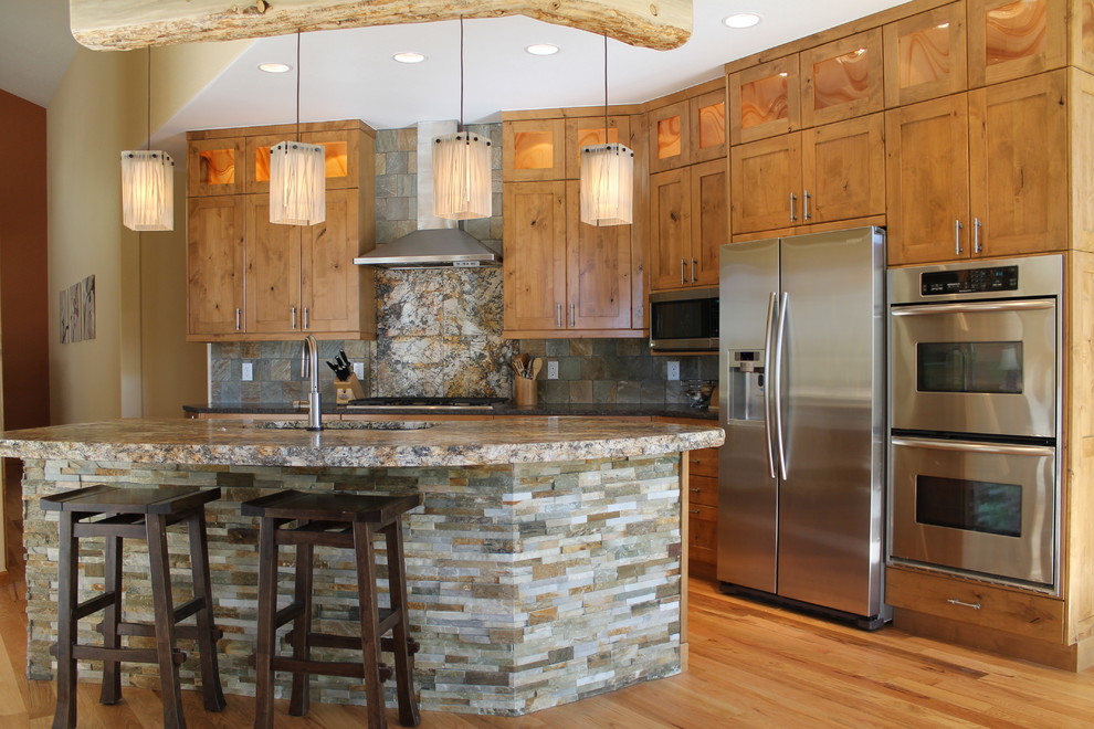 Large mountain style single-wall light wood floor open concept kitchen photo in Denver with an undermount sink, glass-front cabinets, light wood cabinets, granite countertops, gray backsplash, stone tile backsplash, stainless steel appliances and an island