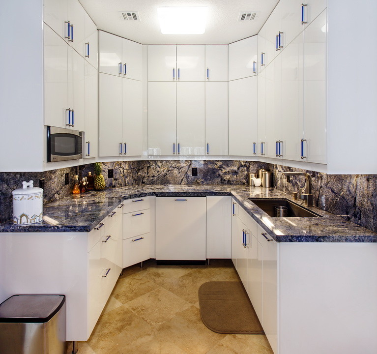 Photo of a contemporary galley kitchen in Miami with granite benchtops, blue splashback, stone slab splashback, an undermount sink, flat-panel cabinets and white cabinets.