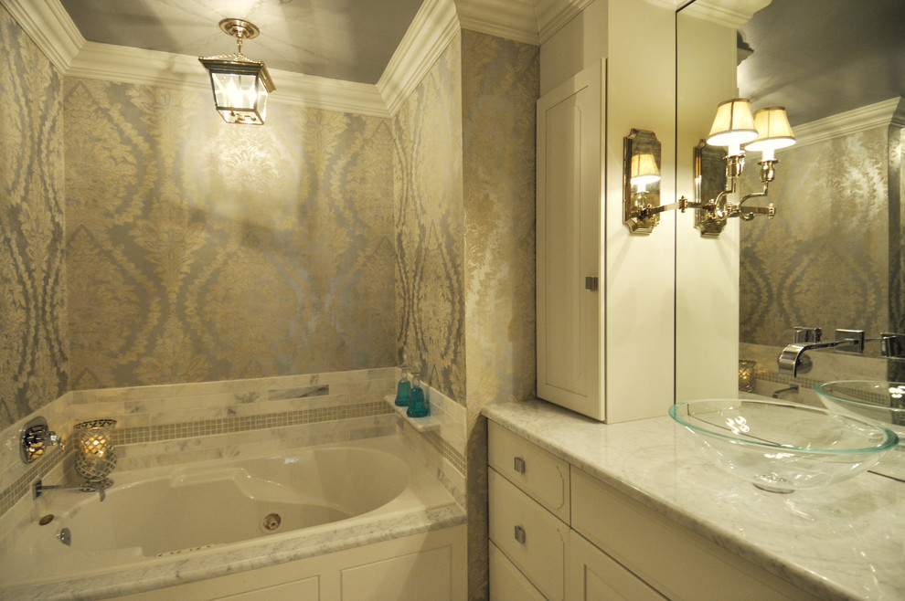 This is an example of a mid-sized eclectic master bathroom in Las Vegas with a vessel sink, raised-panel cabinets, beige cabinets, marble benchtops, an alcove tub, a corner shower, a one-piece toilet, gray tile, stone slab, grey walls and marble floors.