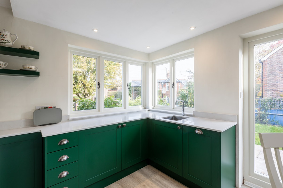 Kleine Klassische Wohnküche in L-Form mit Schrankfronten im Shaker-Stil, grünen Schränken, Quarzit-Arbeitsplatte, schwarzen Elektrogeräten und weißer Arbeitsplatte in Sussex