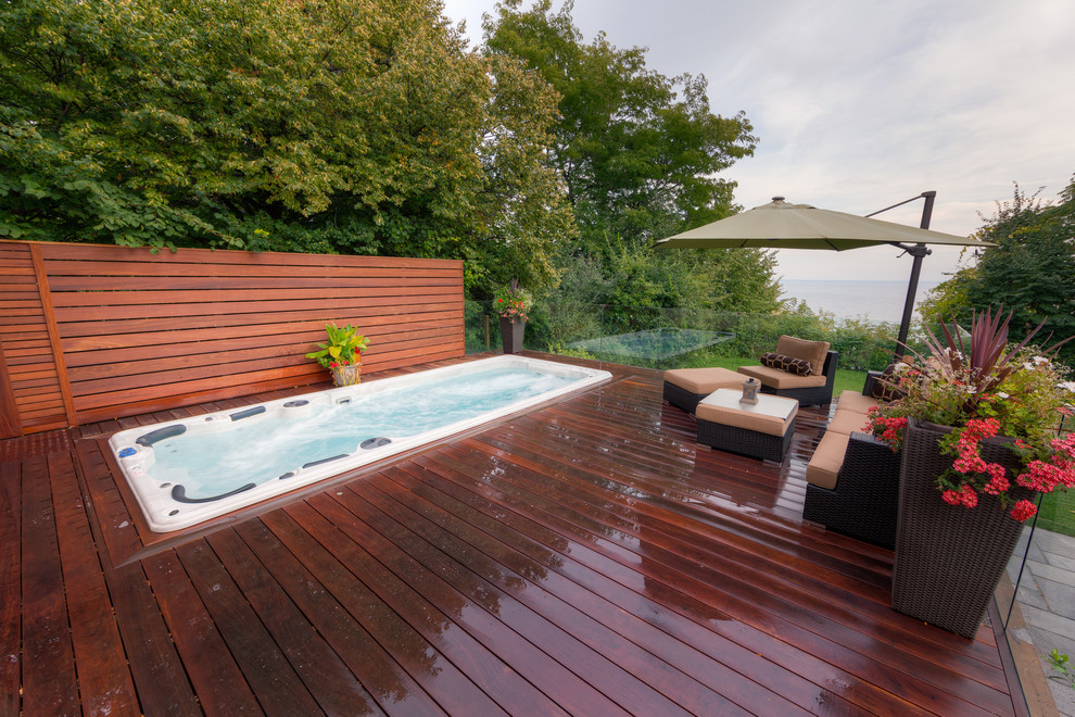 Mid-sized contemporary backyard rectangular lap pool in Toronto with a hot tub and decking.