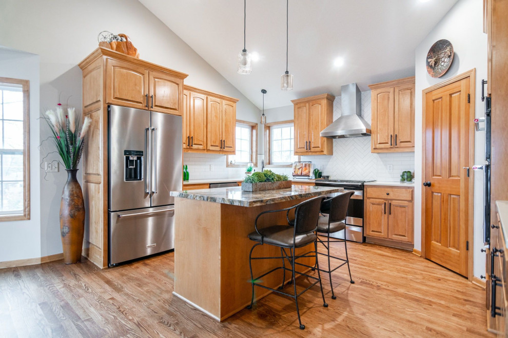 Photo of a medium sized classic u-shaped kitchen/diner in Minneapolis with a double-bowl sink, raised-panel cabinets, medium wood cabinets, engineered stone countertops, white splashback, ceramic splashback, stainless steel appliances, medium hardwood flooring, an island, brown floors and white worktops.
