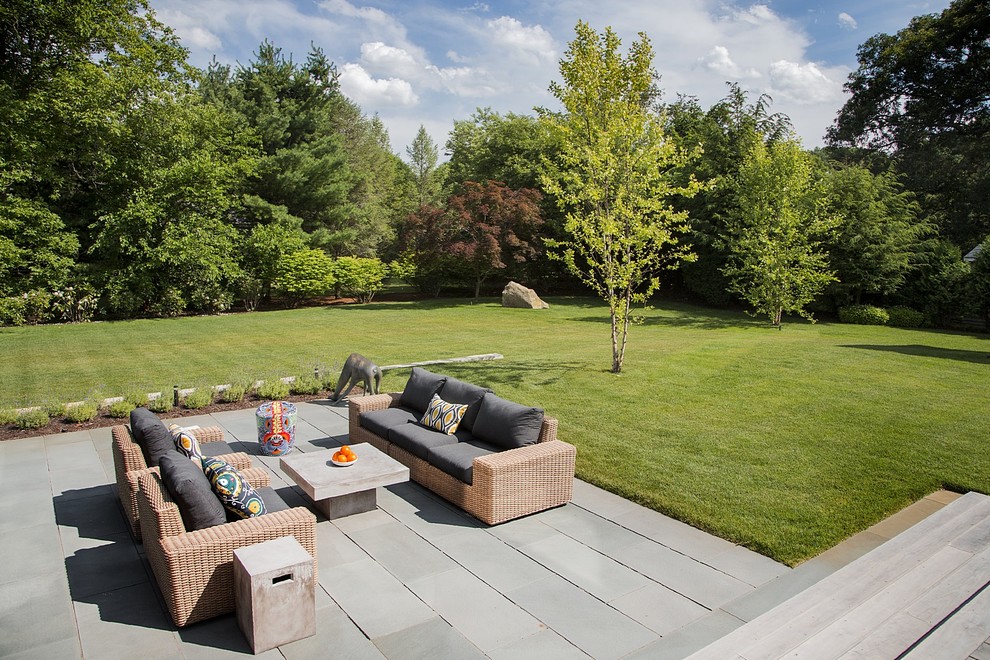 Large modern backyard patio in Boston with natural stone pavers and no cover.