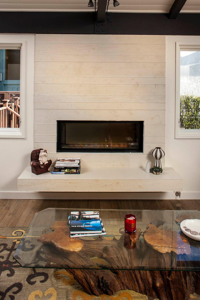 This is an example of a mid-sized contemporary open concept living room in San Diego with white walls, light hardwood floors, a two-sided fireplace, a concrete fireplace surround and a corner tv.